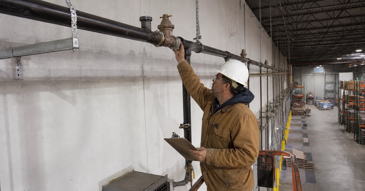An installer pressure testing a gas header inside a distribution building